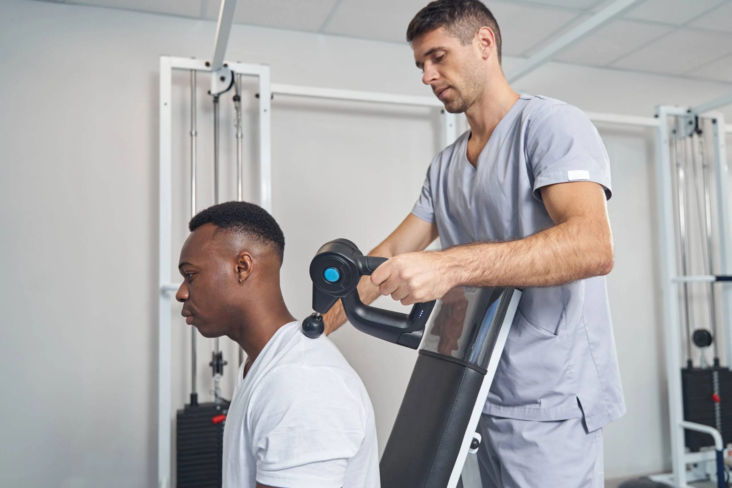 Concentrated physical therapist performing percussive therapy session